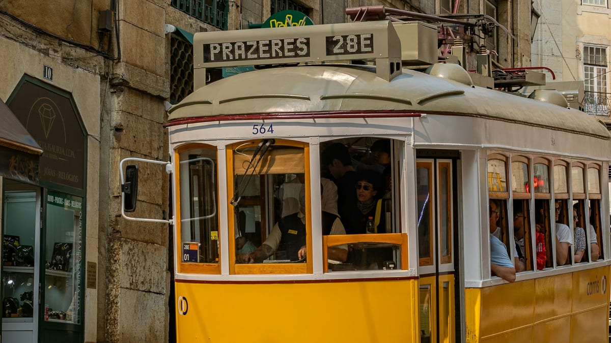 Lisbon yellow tram 28E on a narrow street — Portugal stay, earn and tax hub