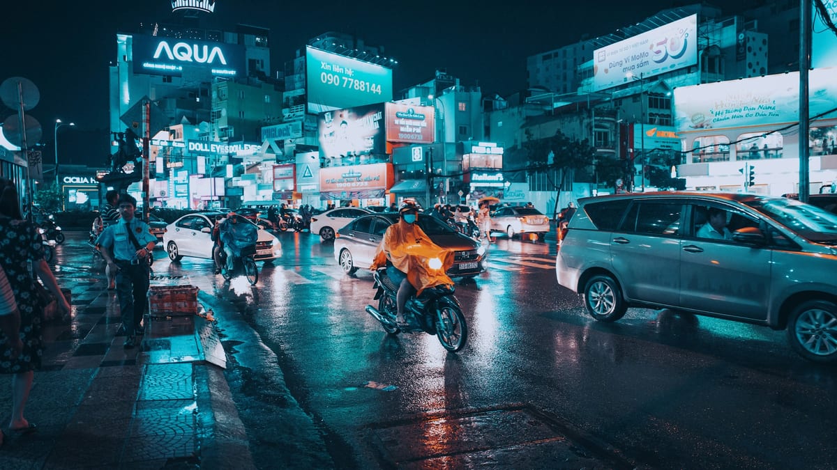 Rainy night street with traffic and billboards in Ho Chi Minh City