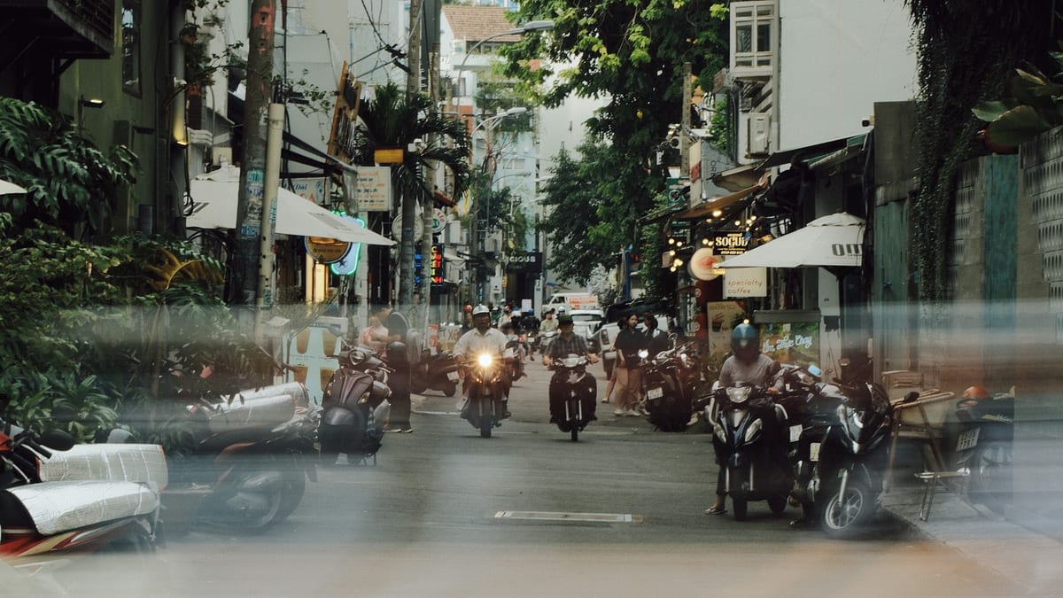 Motorbikes moving through a narrow shop street in Ho Chi Minh City