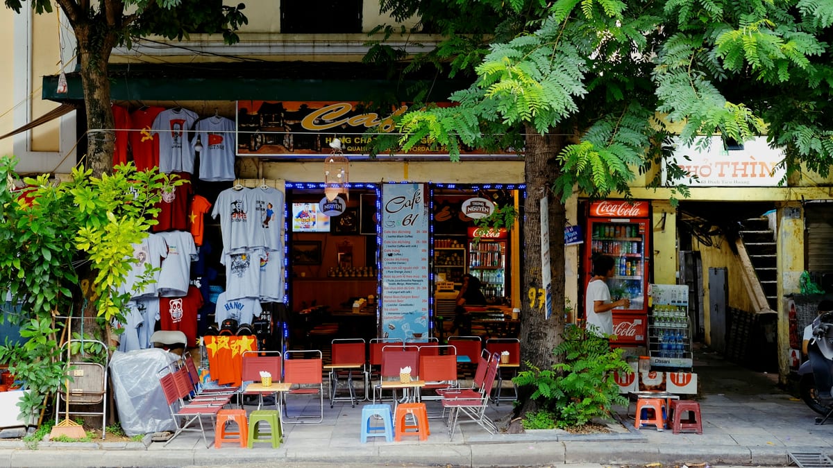 Street cafe with sidewalk stools under trees in Hanoi