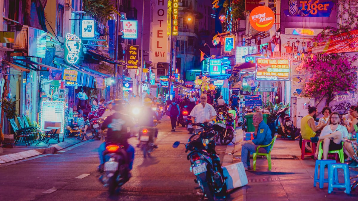 Neon-lit backpacker street with motorbikes at night in Ho Chi Minh City